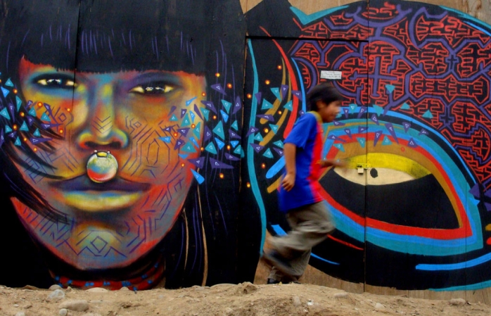 Lima'daki pek çok graffitiden birinin önünden koşarak geçen bir çocuk.