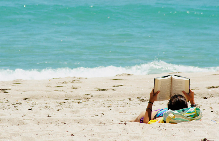 Plajda kitap okuyan bir kız.