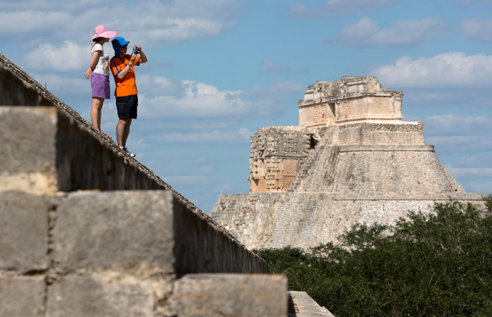 Uxmal’ın merkezindeki Büyücünün Piramidi ve fotoğraf çeken turistler – Yucatan, Meksika