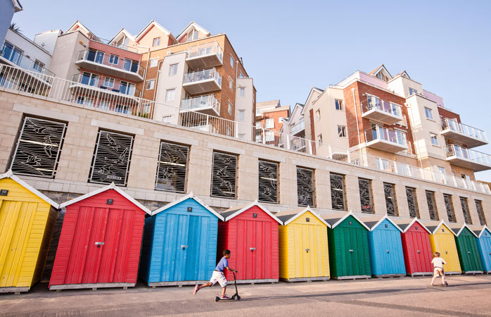 popüler tatil yerleri- Bournemouth’un modern apartmanlarının önündeki renkli ve dikkat çekici plaj kulübeleri