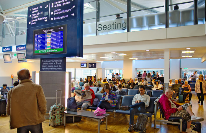 Bir adam kapı numarasını bulmak için giden uçuşlar ekranını kontrol ediyor – Bristol Havalimanı, Birleşik Krallık