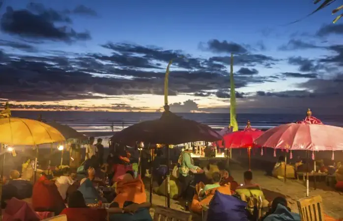 BALI, INDONESIA - FEBRUARY 21, 2014: Tourists enjoy a drink after sunset in a beach bar along Seminyak beach, just north of Kuta, in Bali.