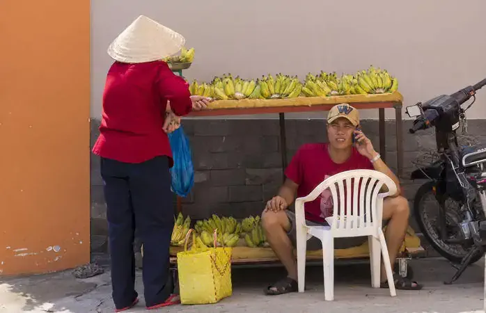 Ho Chi Minh City, Vietnam - August 23, 2014: Street banana seller making call with his cell phone in Ho Chi Minh City on Aug 23, 2014