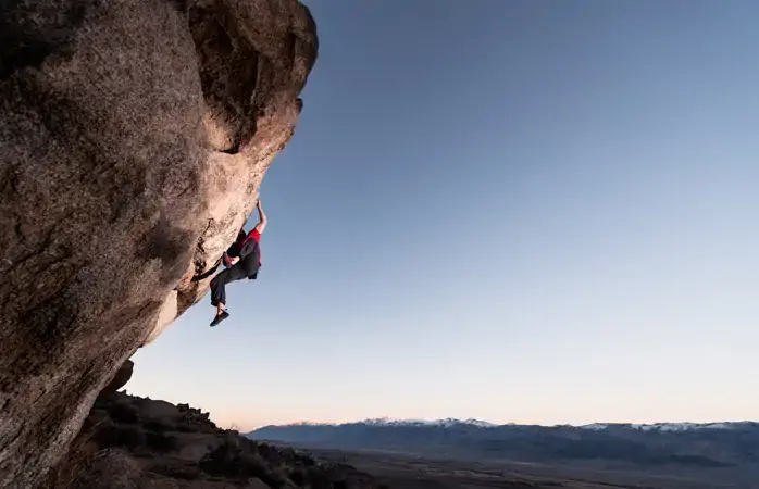 Strong rock climber on a steep boulder at sunset. Location, Bishop CA USA